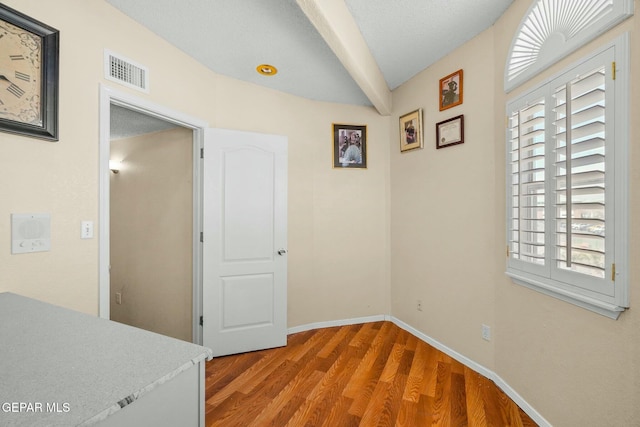 hall featuring wood finished floors, visible vents, and baseboards