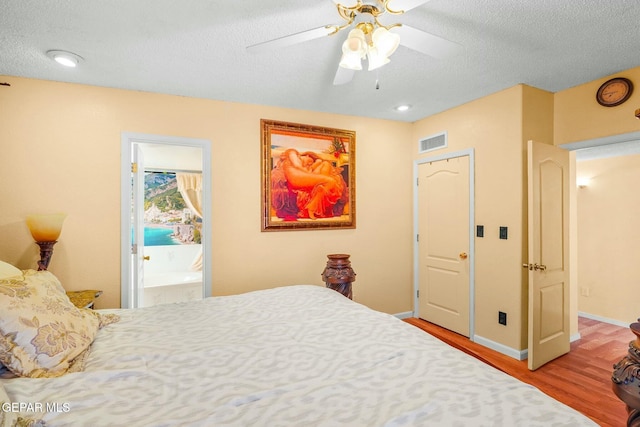 bedroom with baseboards, a textured ceiling, visible vents, and wood finished floors