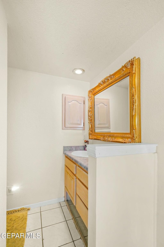 bathroom with a textured ceiling, vanity, baseboards, and tile patterned floors