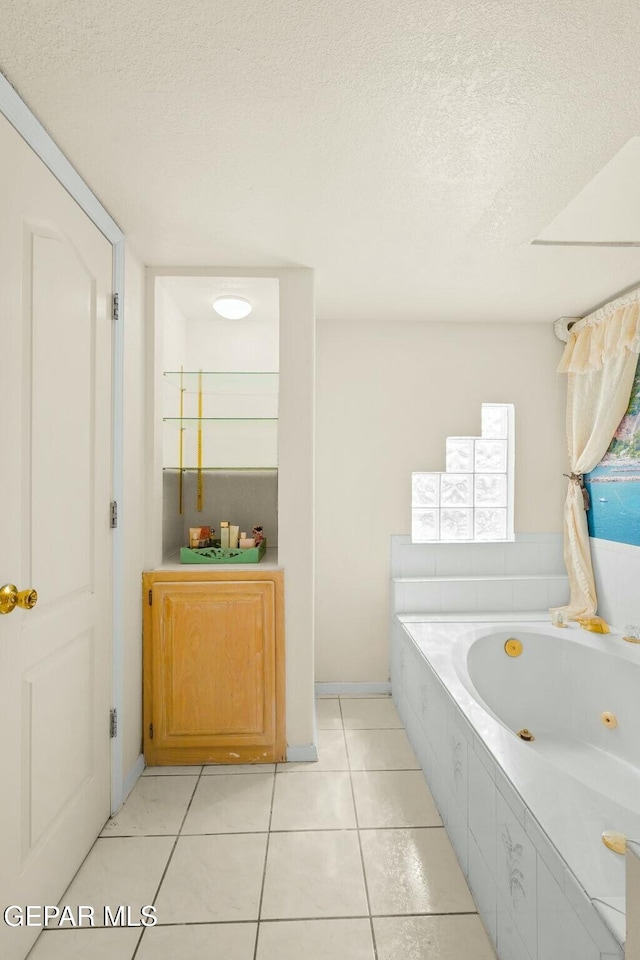 bathroom with a textured ceiling, a whirlpool tub, and tile patterned floors