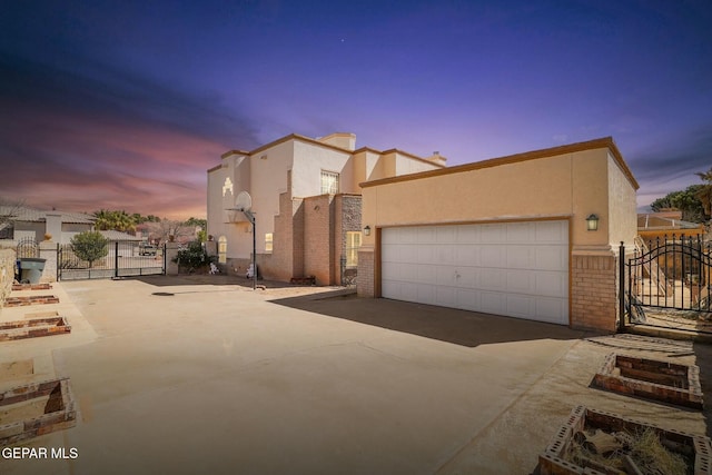 view of front of house with brick siding, stucco siding, a gate, fence, and a garage