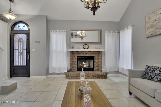 living area featuring baseboards, lofted ceiling, tile patterned floors, a brick fireplace, and a notable chandelier