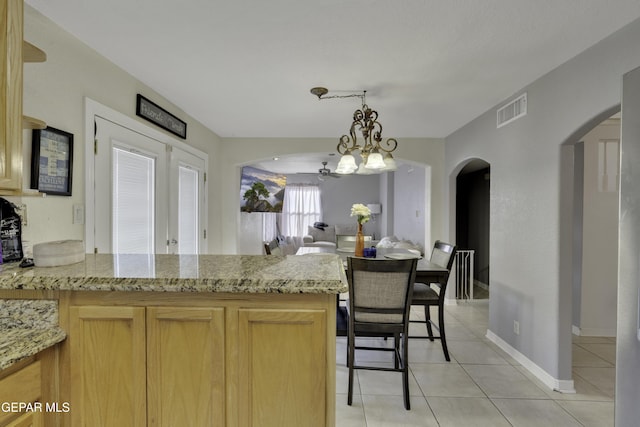 kitchen with visible vents, arched walkways, a peninsula, hanging light fixtures, and light tile patterned flooring