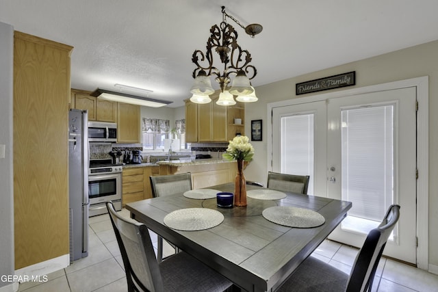 dining area featuring light tile patterned floors, french doors, and a textured ceiling