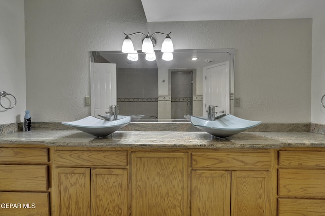 bathroom with a textured wall, a sink, and double vanity