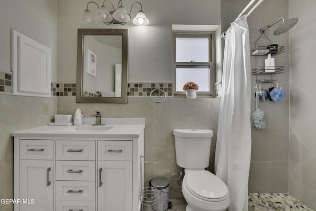 bathroom featuring toilet, tiled shower, vanity, and tile walls