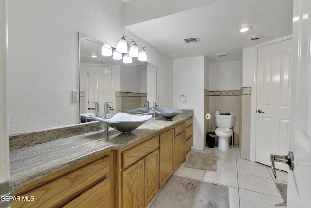 full bath with toilet, visible vents, a sink, and tile patterned floors