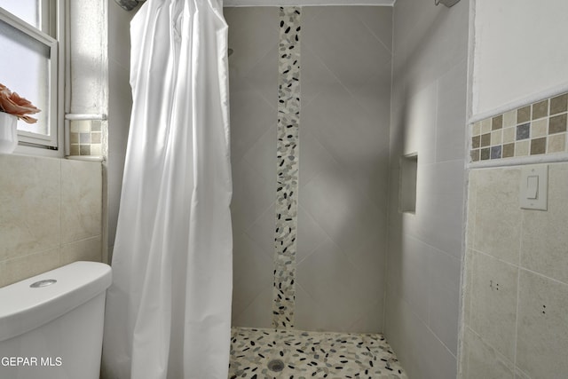 bathroom with tile walls, a shower stall, and toilet