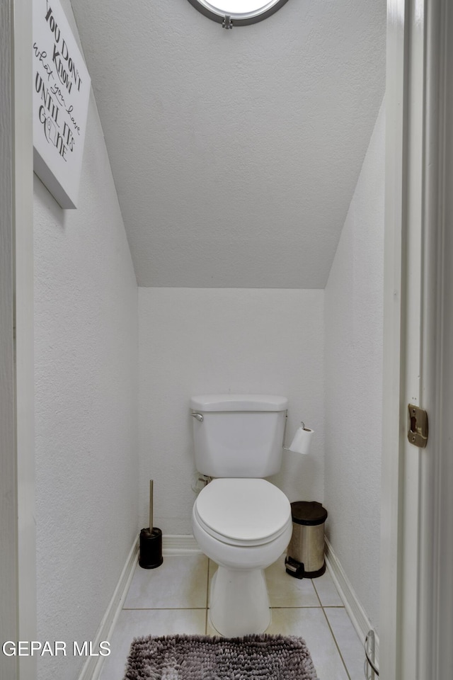 bathroom featuring toilet, tile patterned flooring, baseboards, and lofted ceiling