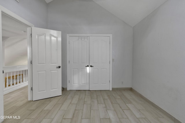 unfurnished bedroom with light wood-style floors, high vaulted ceiling, and a closet