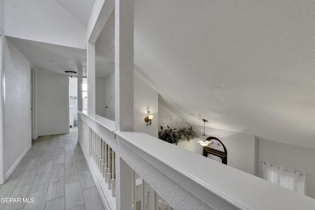 hall featuring baseboards, vaulted ceiling, and wood finish floors