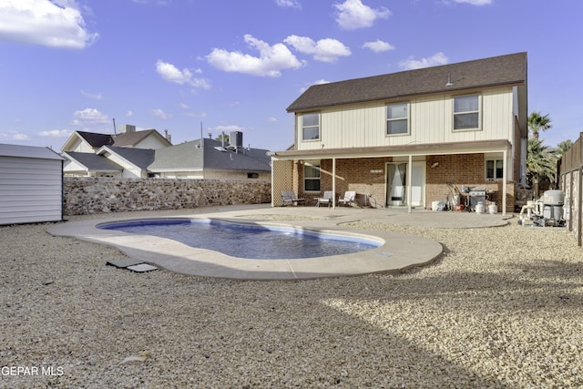 back of house with an outbuilding, a patio, a fenced backyard, brick siding, and a fenced in pool