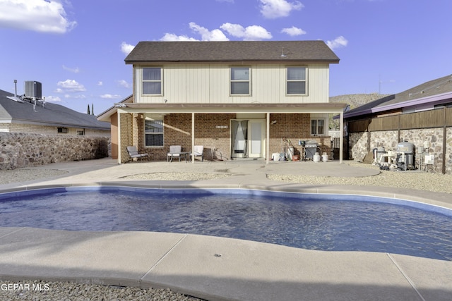 pool with grilling area, cooling unit, and a patio