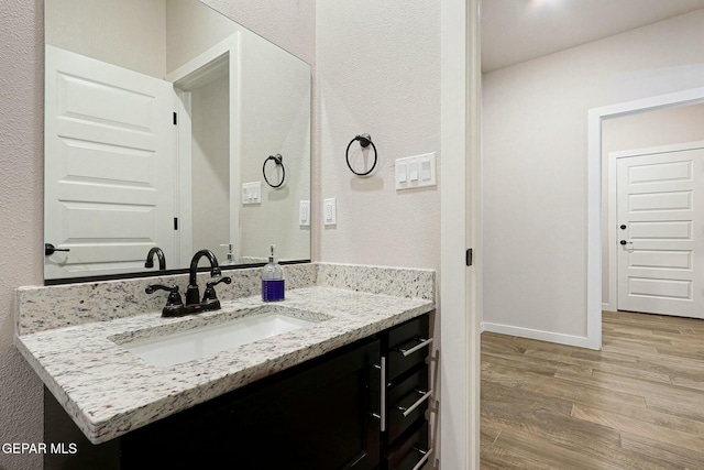 bathroom featuring vanity, baseboards, and wood finished floors