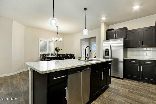 kitchen with stainless steel appliances, dark wood-type flooring, a sink, and a center island with sink