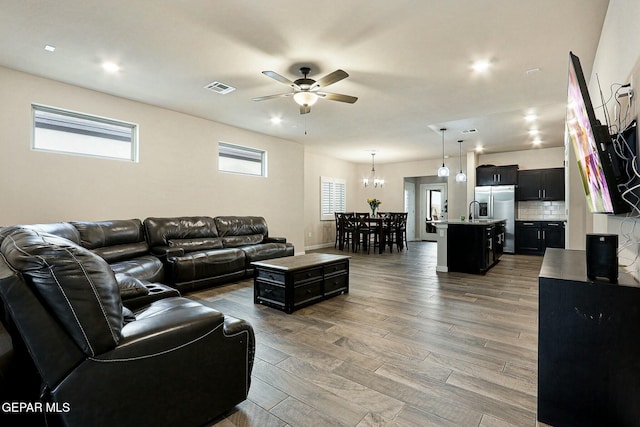 living room featuring ceiling fan with notable chandelier, wood finished floors, visible vents, and recessed lighting