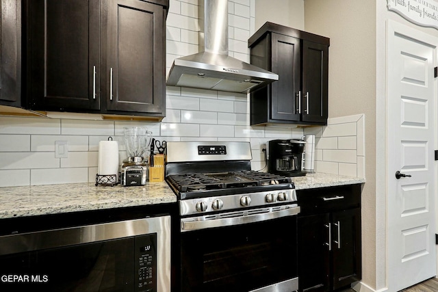 kitchen featuring stainless steel gas range, wall chimney exhaust hood, black microwave, and decorative backsplash