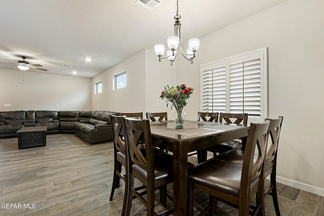 dining space with visible vents, light wood-style flooring, baseboards, and ceiling fan with notable chandelier