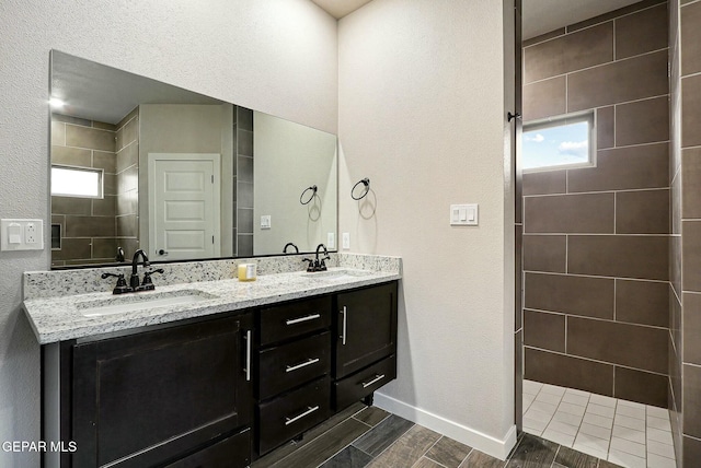 bathroom with a wealth of natural light, wood finish floors, a sink, and double vanity