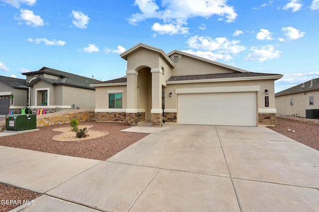 view of front of property with stone siding, an attached garage, driveway, and stucco siding