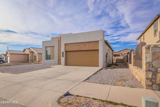 southwest-style home featuring an attached garage, fence, concrete driveway, and stucco siding