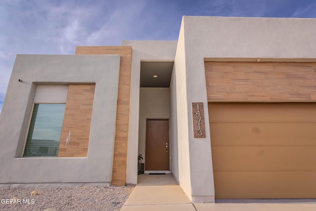 doorway to property with a garage and stucco siding