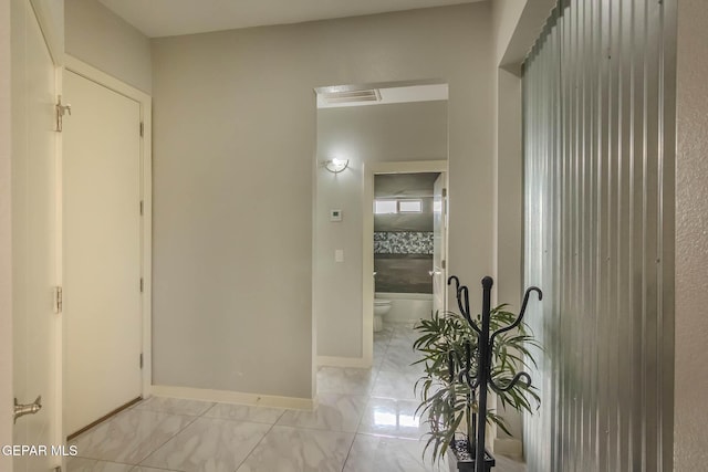 corridor featuring marble finish floor, visible vents, and baseboards