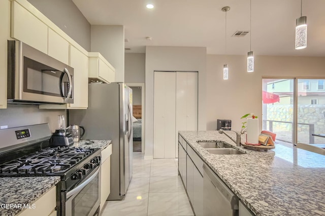 kitchen with visible vents, light stone counters, decorative light fixtures, stainless steel appliances, and a sink