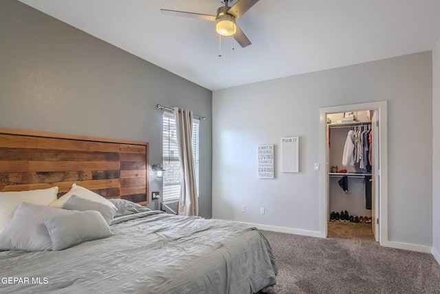 carpeted bedroom with a spacious closet, baseboards, and a ceiling fan