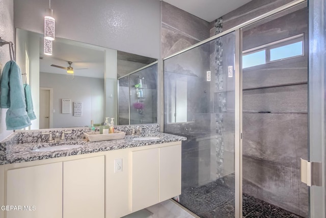 full bath with ceiling fan, a stall shower, a sink, and double vanity