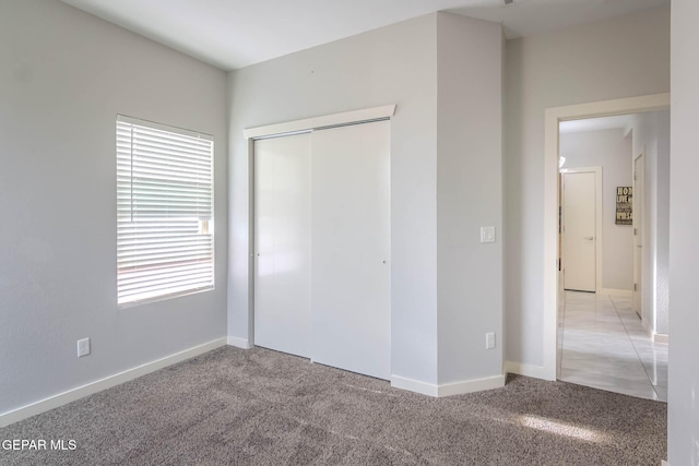 unfurnished bedroom with light carpet, baseboards, and a closet