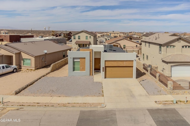 view of front facade featuring a garage, driveway, a residential view, and stucco siding