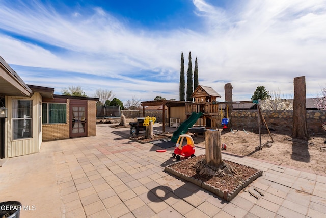 view of patio / terrace featuring a trampoline, a playground, and fence