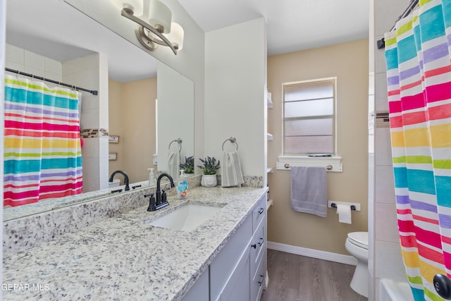 bathroom featuring a shower with shower curtain, wood finished floors, vanity, and baseboards