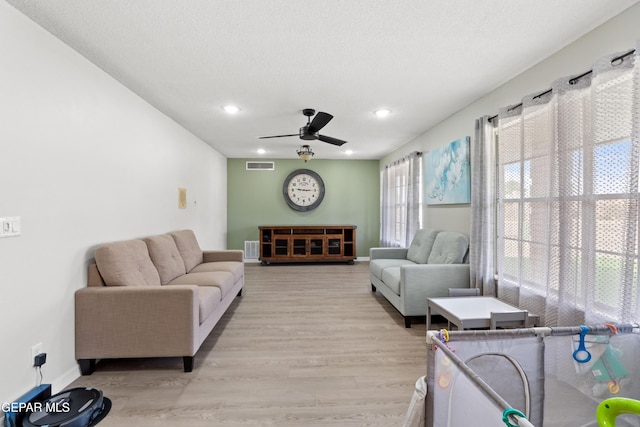 living area featuring a ceiling fan, visible vents, light wood-style flooring, and baseboards