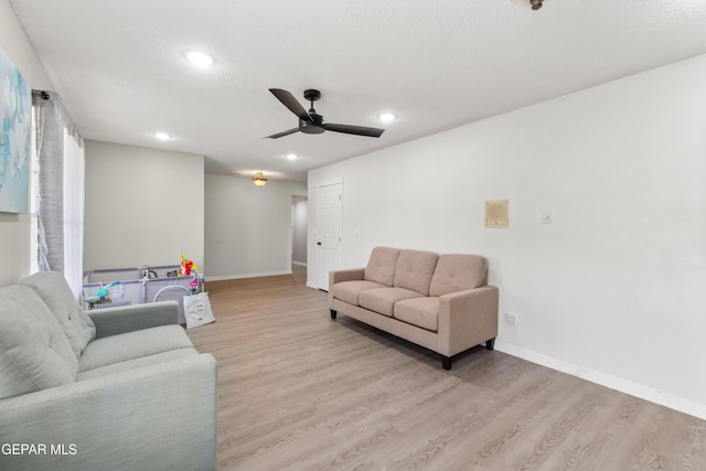 living room with recessed lighting, a textured ceiling, baseboards, and wood finished floors