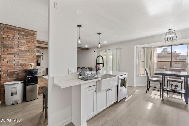 kitchen featuring dishwasher, a sink, light wood-style flooring, and white cabinets