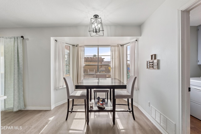 dining space featuring light wood-style flooring, visible vents, and baseboards