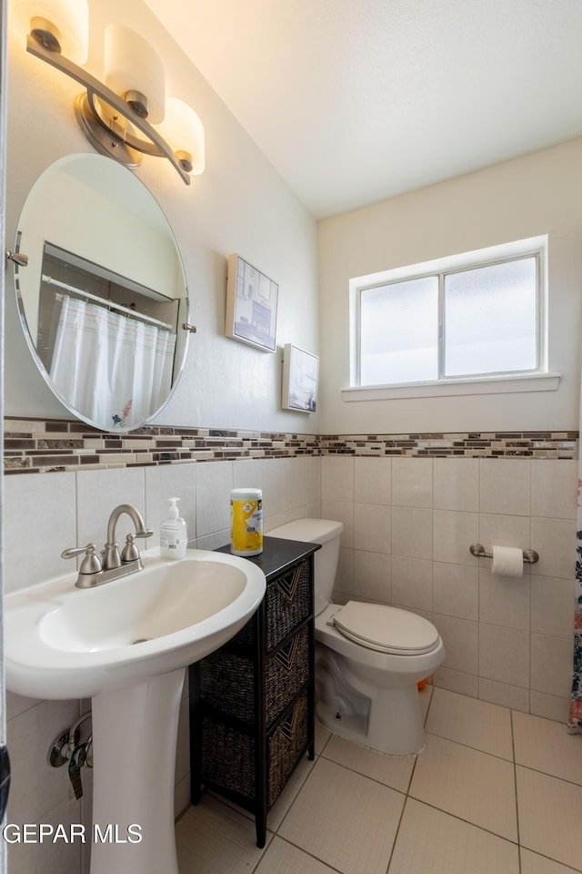 bathroom with toilet, tile patterned flooring, tile walls, and a shower with shower curtain