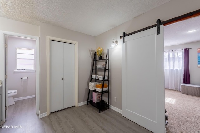 bathroom with a textured ceiling, wood finished floors, toilet, and baseboards