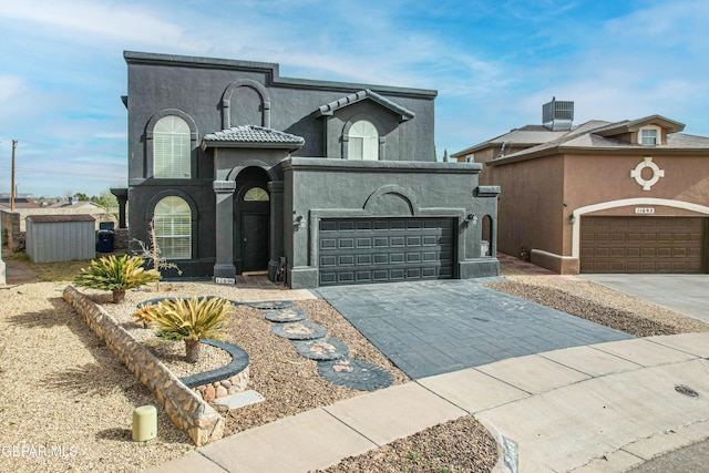 view of front of home featuring a garage, decorative driveway, a tile roof, and stucco siding