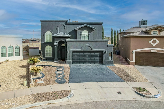 view of front facade with an attached garage, central AC, decorative driveway, and stucco siding