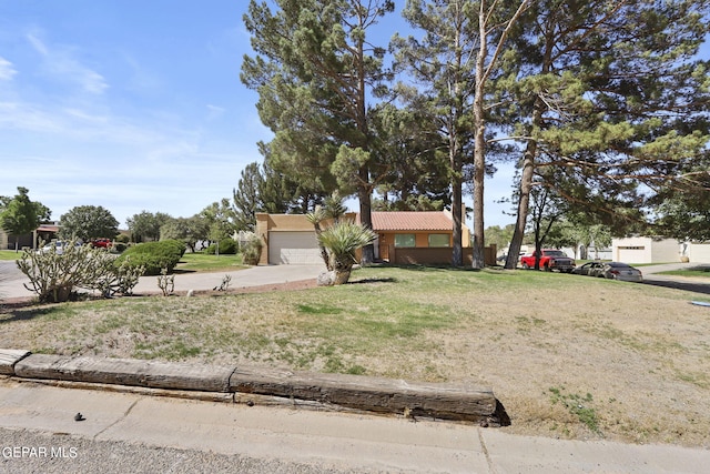 view of front of property featuring a garage, a tile roof, and a front lawn