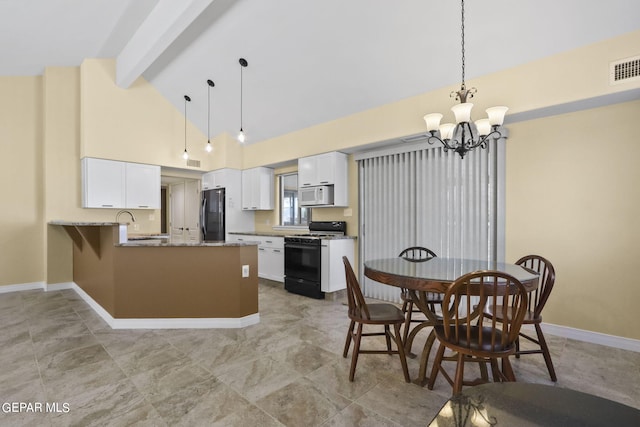 kitchen featuring white microwave, a peninsula, range with gas stovetop, freestanding refrigerator, and beamed ceiling