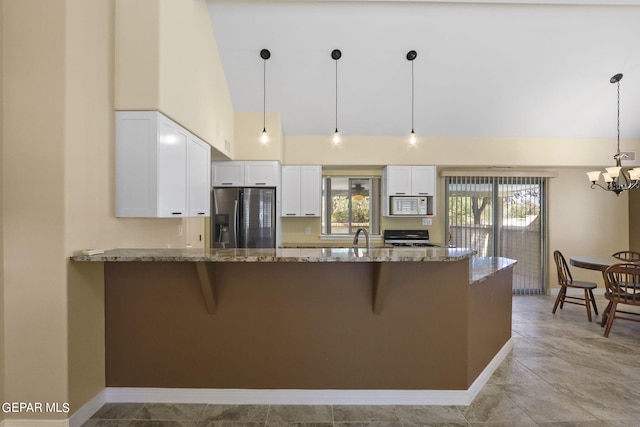 kitchen featuring white microwave, stove, white cabinets, stainless steel refrigerator with ice dispenser, and light stone countertops