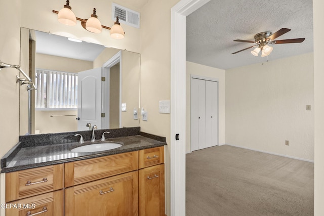 bathroom with a textured ceiling, vanity, visible vents, and a ceiling fan