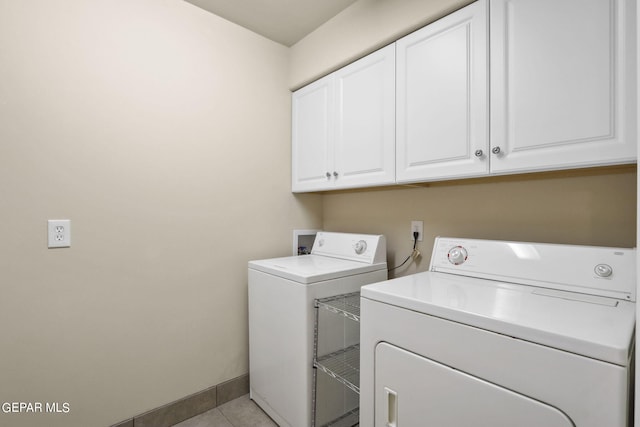 laundry area with baseboards, light tile patterned floors, cabinet space, and washer and dryer