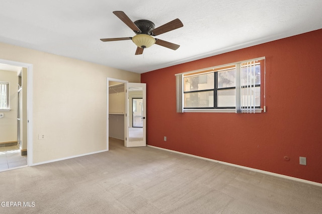 unfurnished bedroom featuring carpet floors, baseboards, a walk in closet, and a closet