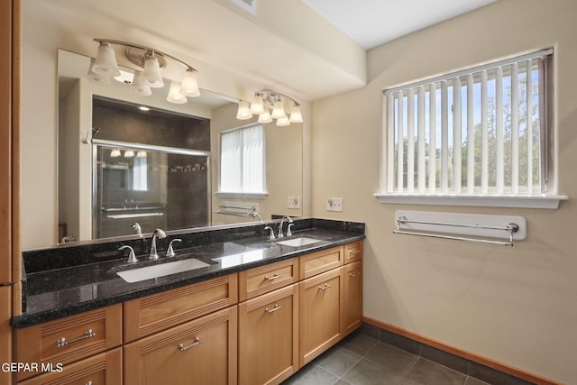 full bath featuring double vanity, a stall shower, tile patterned flooring, and a sink