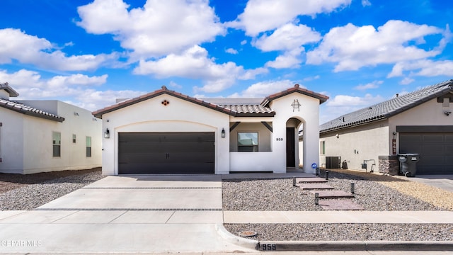 mediterranean / spanish home with a garage, concrete driveway, a tiled roof, and stucco siding